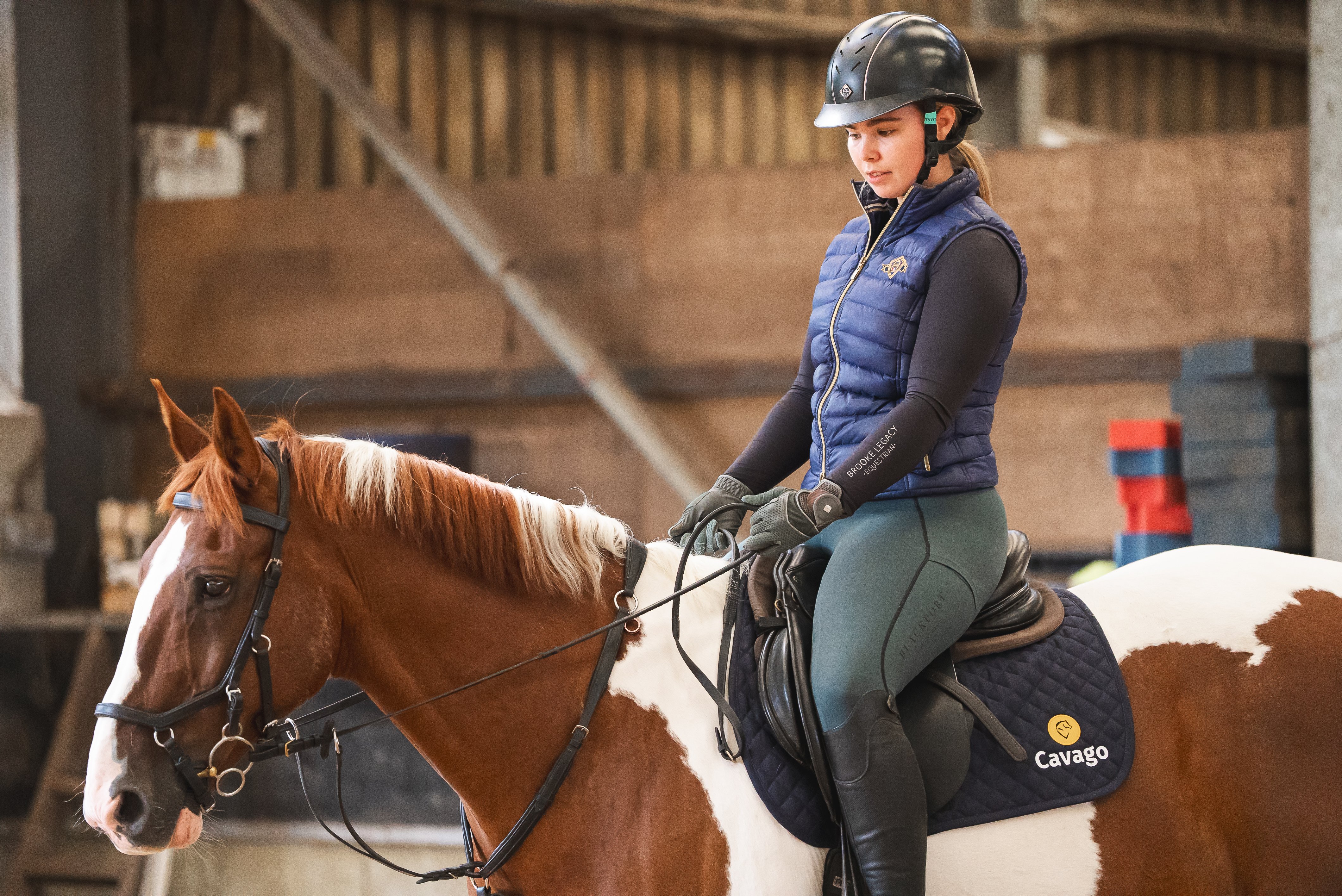 Woman riding a brown and white horse wearing a helmet.